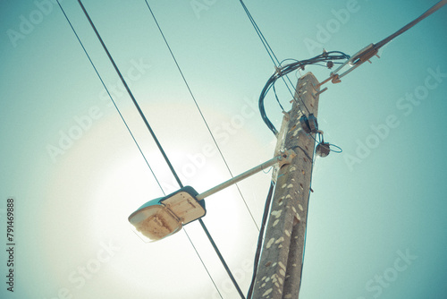 Low angle view of utility pole with electrical wires and a streetlight against a clear sky