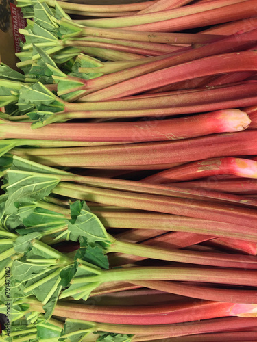 Close-up of a heap of organic cultivated red rhubarb stalks ready for sale at farmers market in spring.