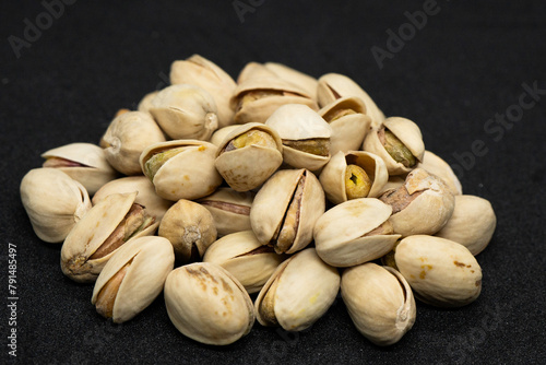 Roasted pistachio nuts in shell on black background (Antep Fistigi), poured roasted peanuts (Pistachio) photo