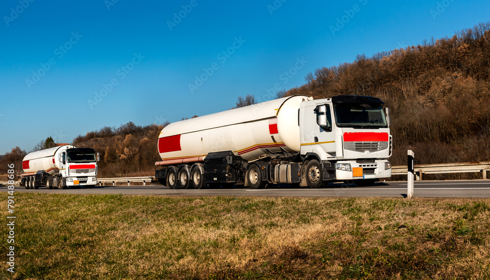 Gasoline tankers, Oil trailers, Tank trucks on highway close up on a Highway road with a beautiful sky in the background Gasoline tankers, Oil trailers, Tank trucks on highway close up on a Highway road with a beautiful sky in the background