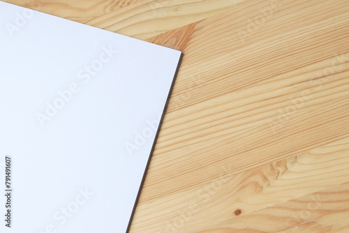 White blank paper on a wooden table, top view. A small stack of A4 sheets on the desktop, close-up. Blank paper, space for text, mockup