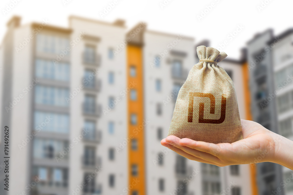 Israeli shekel bag against the background of modern high-rise buildings. Investing in the purchase of real estate. Affordable housing and mortgage rates. Renting apartments and houses. Blurred - obrazy, fototapety, plakaty 