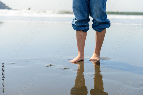 波打ち際を裸足で歩く女性