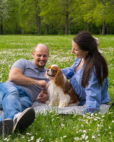Happy pregnant couple spends time together on a picnic outdoors with a pet, dog, cocker spaniel. Waiting for a baby, love