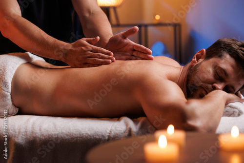 The hands of the male masseur are actively rubbing the visitors back, a therapeutic massage for tired muscles. Point massage in the spa center. Body therapy for a healthy lifestyle.