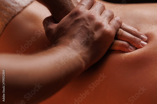 Extreme closeup of masseurs male hands gently pressing hands along clients back. Concept of aesthetic relaxing massage in spa salon, recovery, reboot.