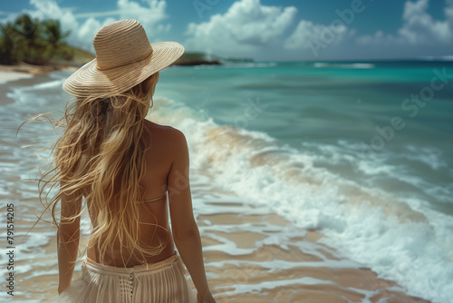 Donna al mare cammina in riva alla spiaggia con cappello di paglia photo