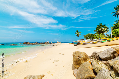 Boats on the sand in a tropical beach under a blue sky