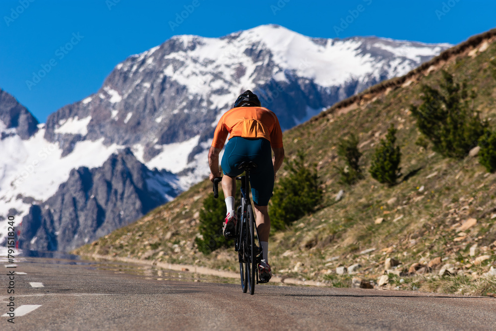 A man is riding a bike down a road with a mountain in the background