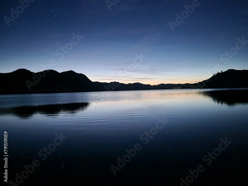 Tranquil lake with mountains under the evening sky