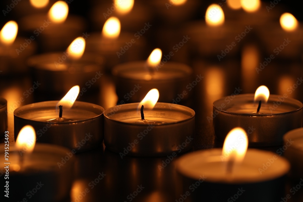 Burning tealight candles on dark surface, closeup Burning tealight candles on dark surface, closeup