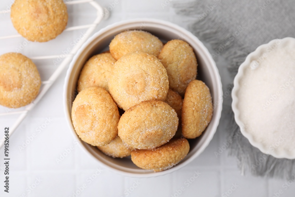 Tasty sugar cookies in bowl on white tiled table, top view