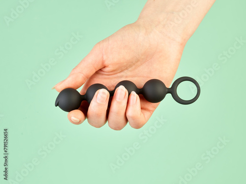 Woman's hand holding adult sex toy over mint background