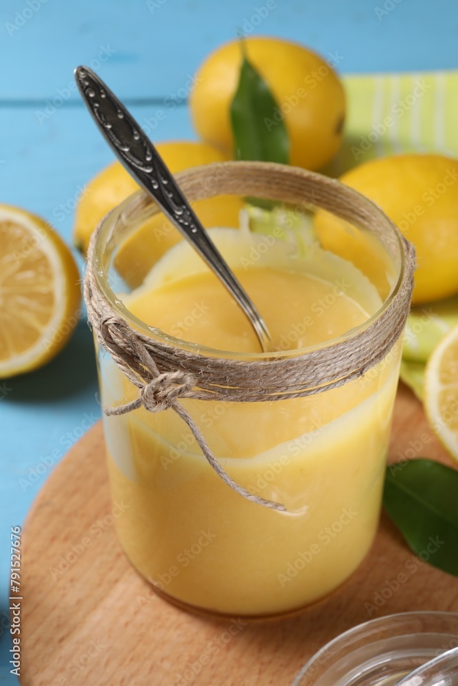 Delicious lemon curd in glass jar, fresh citrus fruits and spoon on light blue table, closeup Delicious lemon curd in glass jar, fresh citrus fruits and spoon on light blue table, closeup