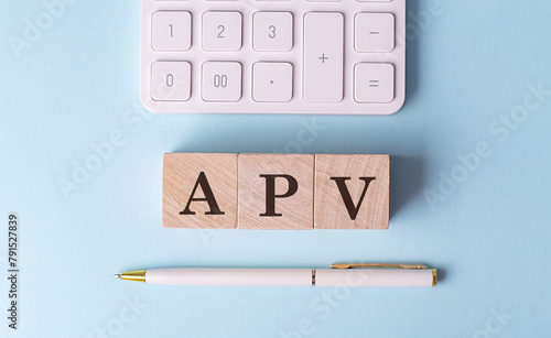 Obraz na plátně APV word on wooden block with pen and calculator on blue background