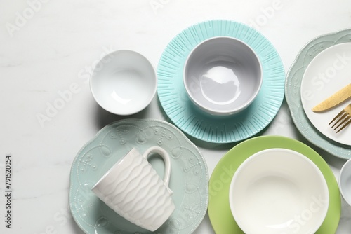 Beautiful ceramic dishware  cup and cutlery on white marble table  flat lay