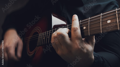 A man in a black shirt plays an acoustic guitar