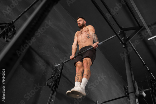 Strong man performing muscle up on bars. Crossfit workout for physical and mental health.