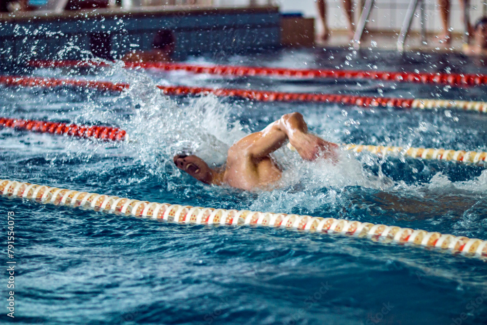 A swimmer in a cap and goggles swims crawl in the pool	
