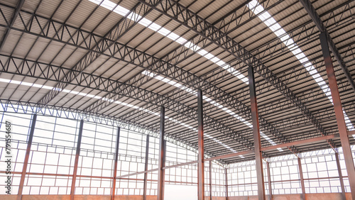 Steel wall framework structure with metal columns and curve roof beams inside of large industrial factory building in construction site, low angle and perspective side view © Prapat