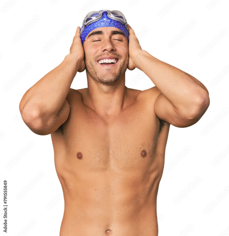 Young Hispanic man with swim gear laughs joyfully keeping hands on head. Happiness concept. Young Hispanic man with swim gear laughs joyfully keeping hands on head. Happiness concept.