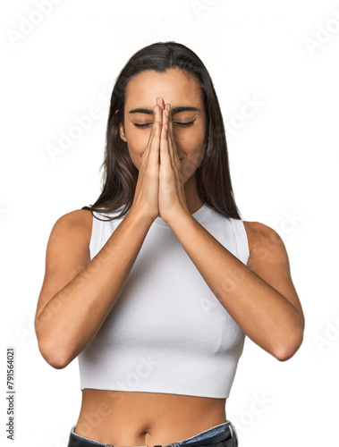 Hispanic young woman holding hands in pray near mouth, feels confident.