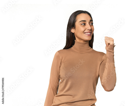 Hispanic young woman points with thumb finger away, laughing and carefree.