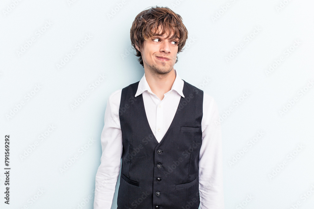 Young caucasian waitress man isolated on blue background confused, feels doubtful and unsure. Young caucasian waitress man isolated on blue background confused, feels doubtful and unsure.
