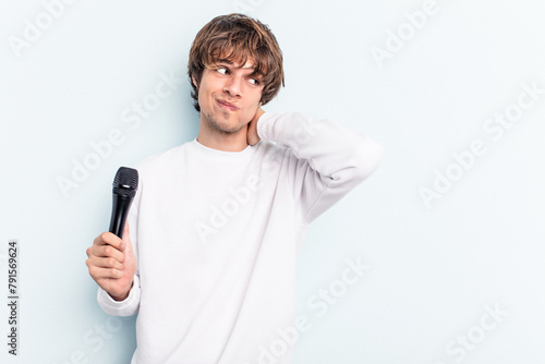 Young caucasian singer man isolated on blue background touching back of head, thinking and making a choice.