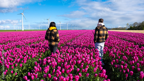 Two people standing gracefully in a vibrant field of purple tulips, surrounded by the beauty of a Dutch spring