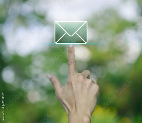 Hand pressing email flat icon over blur green tree in park, Business contact us online concept