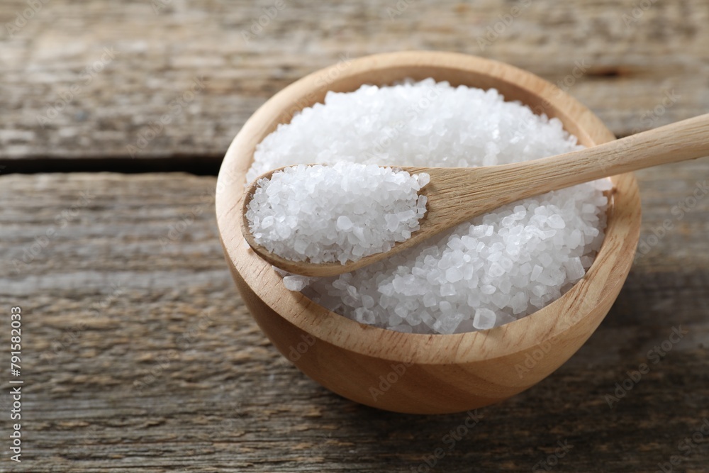 Organic salt in bowl and spoon on wooden table, closeup. Space for text Organic salt in bowl and spoon on wooden table, closeup. Space for text