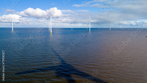 A picturesque scene of a large body of water with numerous windmills in the background, creating a harmonious blend of man-made structures and natural elements © Fokke Baarssen