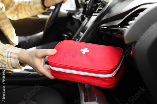 Man with first aid kit inside car, closeup