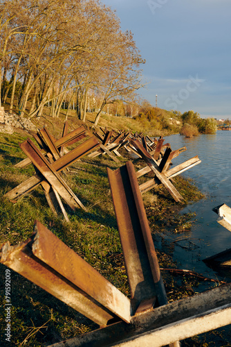 Rusty anti tank hedgehoges on bank of Danube river. Metallic military obstacles constructions protecting freedom, independence of Ukraine 2022 photo