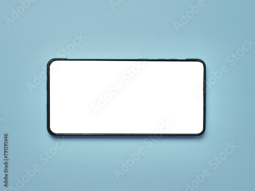 White copy space blank empty smart phone screen, laying on blue desk, top view flat lay