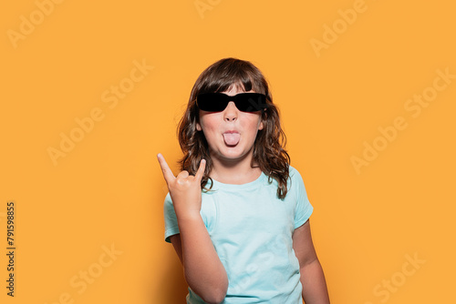 Child in Sunglasses Posing with Rock Gesture in Studio photo
