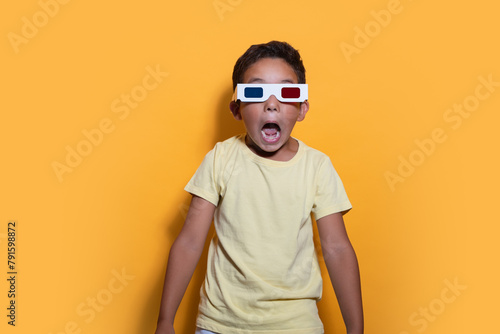 Excited child with 3D glasses on a yellow background photo