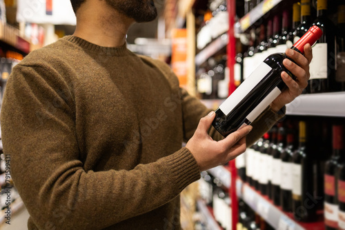 Man carefully selecting wine in supermarket photo