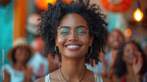 A photo of a young woman with curly hair and glasses smiling.