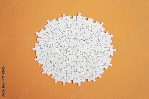 Plain white jigsaw puzzle  on orange color background, oval shaped frame, abstract backdrop