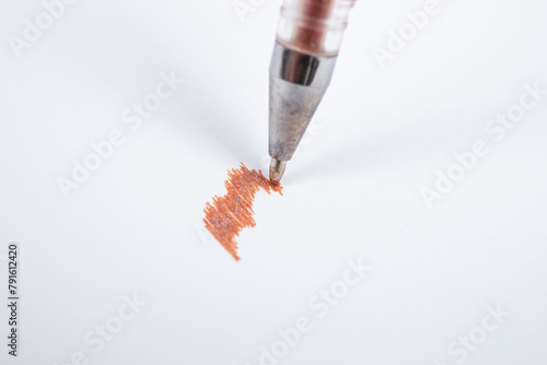 Brown glitter ink ball pen scribbling on white paper, soft focus macro