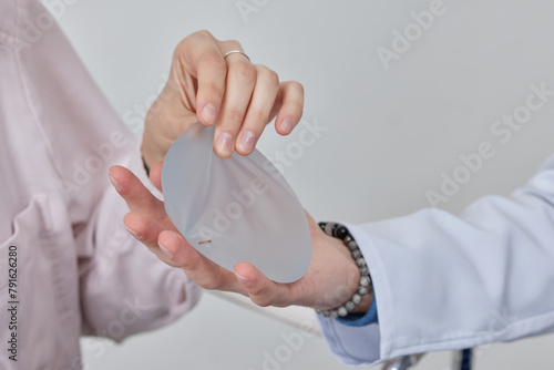 Professional plastic surgeon showing silicone breast implants to his female patient, mastopexy concept, BREAST LIFT photo