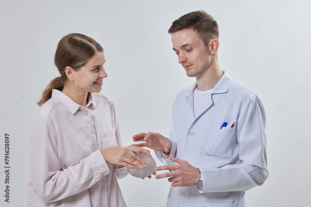 Professional plastic surgeon showing silicone breast implants to his female patient, mastopexy concept, BREAST LIFT Professional plastic surgeon showing silicone breast implants to his female patient, mastopexy concept, BREAST LIFT