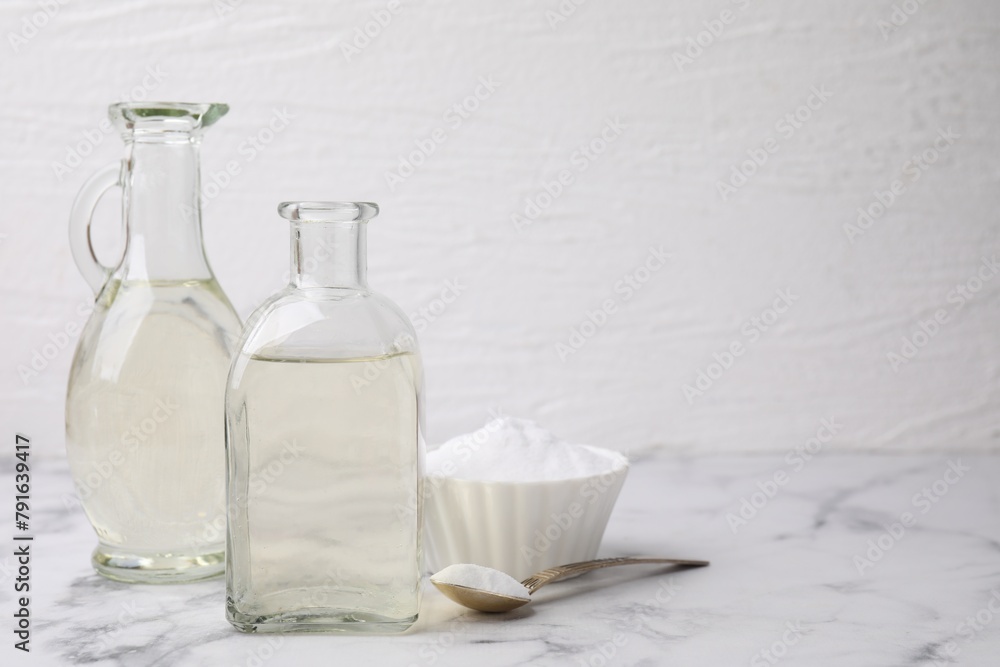 Vinegar and baking soda on white marble table, space for text Vinegar and baking soda on white marble table, space for text