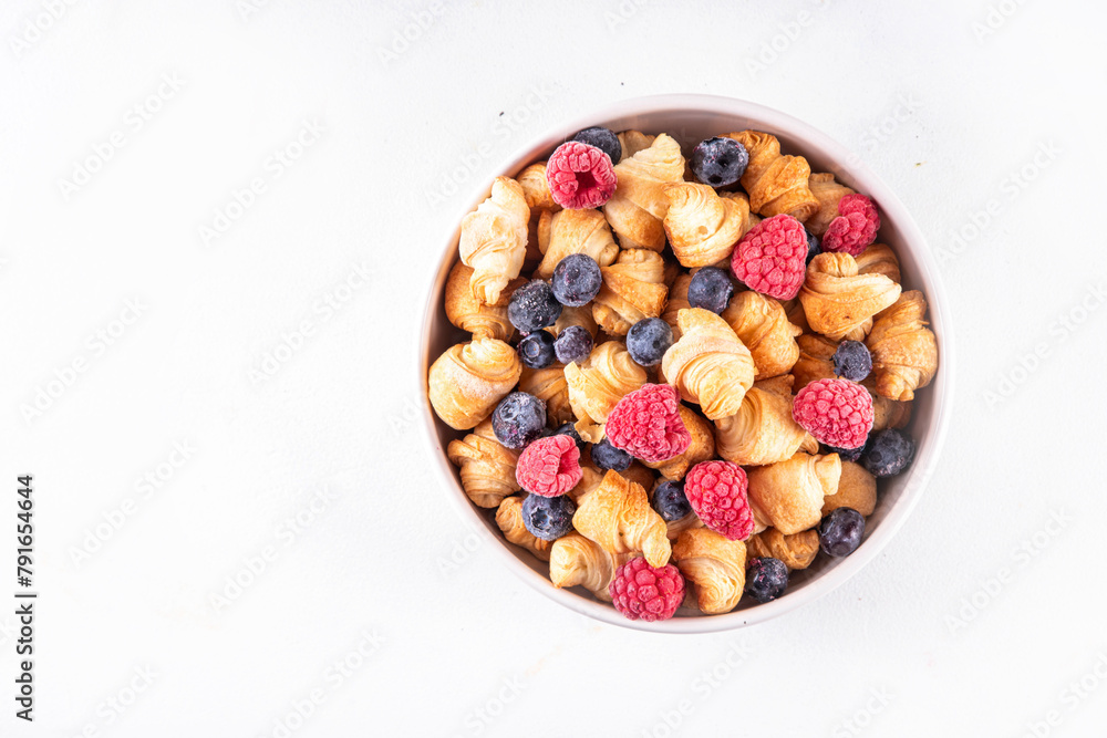 Tiny breakfast croissants cereals with fresh berries and milk. Bowl portions with trendy fresh baked mini petite croissants with raspberry and blueberry, dessert morning snack Tiny breakfast croissants cereals with fresh berries and milk. Bowl portions with trendy fresh baked mini petite croissants with raspberry and blueberry, dessert morning snack