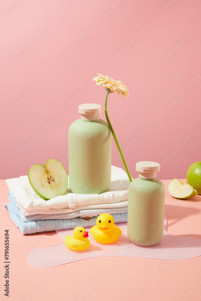 Bathroom layout with many products and toys for baby, Empty label bottle for advertising product made from organic ingredients over light pink background. Front view, copy space Bathroom layout with many products and toys for baby, Empty label bottle for advertising product made from organic ingredients over light pink background. Front view, copy space
