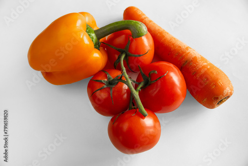 Red and orange vegetables, pepper, tomato and carrot on white background