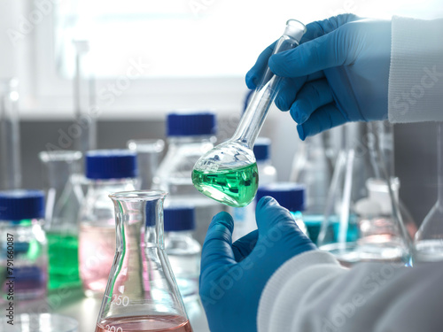 Scientist pouring liquid into flask in laboratory photo