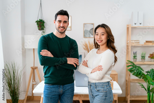 Confident man and woman posing with arms crossed in a modern office. photo